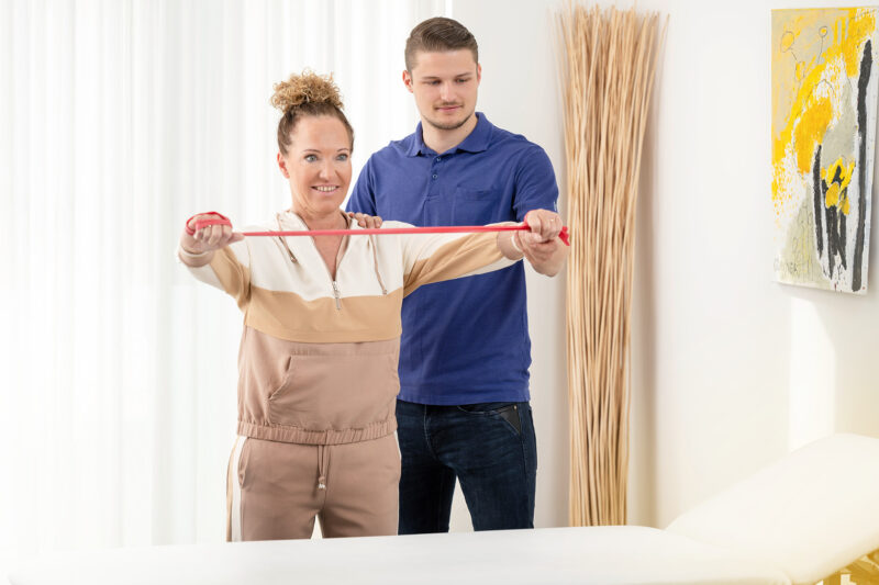 Physiotherapeut und Patientin mit Theraband