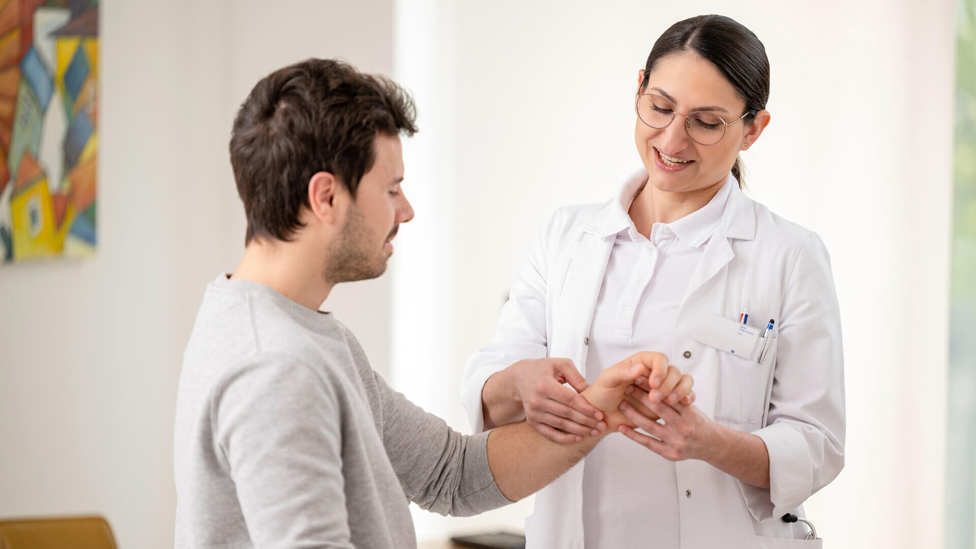 Ärztin schaut sich die Hand des Patienten an